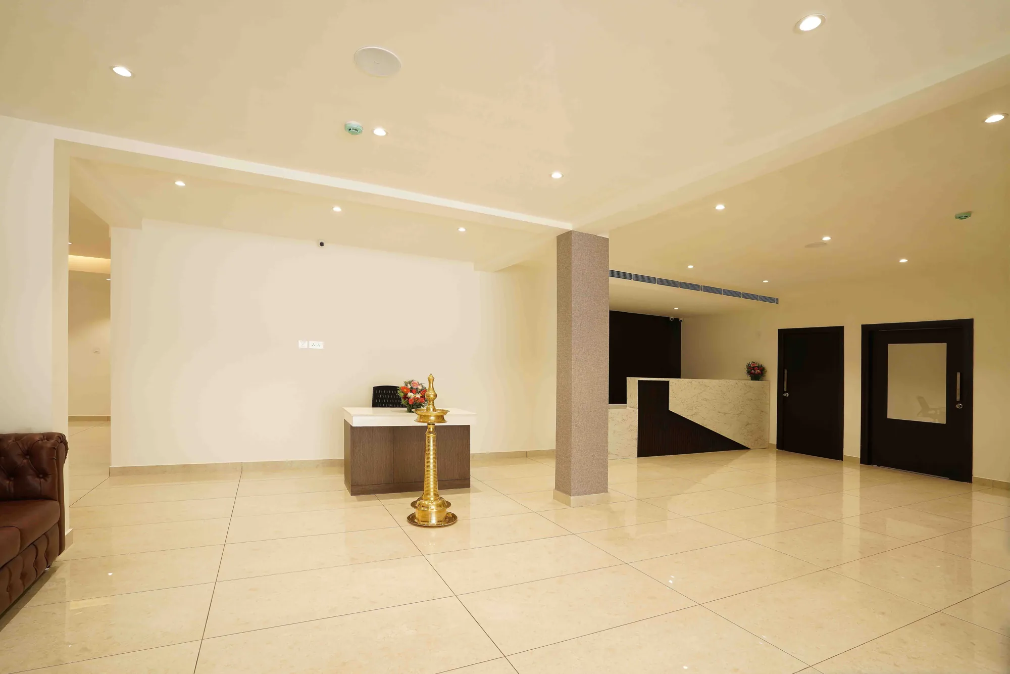 The lobby, with a brass nilavilakku lamp on a polished marble floor