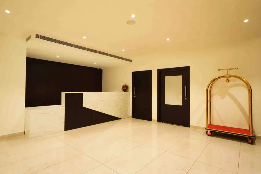 The reception desk in white marble and dark wood, with a brass luggage cart